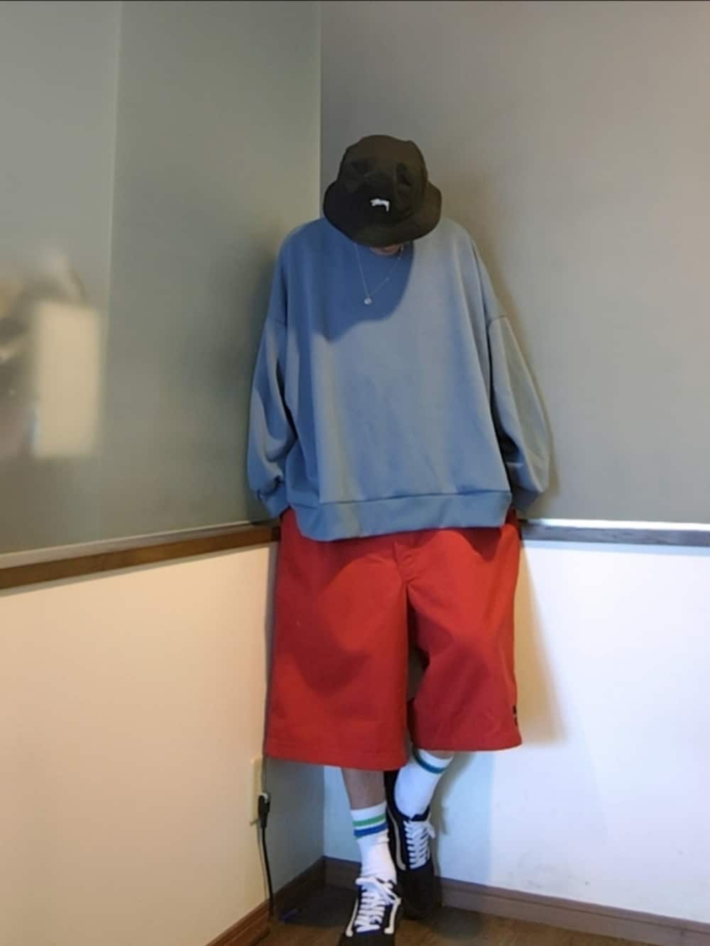 レッド系のチノパンツ、ブルー系のスウェット、ブラック系のスニーカーを着用したメンズの夏コーディネートの2枚目の写真