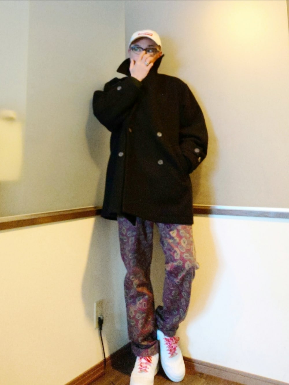 ブラック系のピーコート、レッド系のチノパンツ、ホワイト系のスニーカーを着用したメンズの冬コーディネートの2枚目の写真