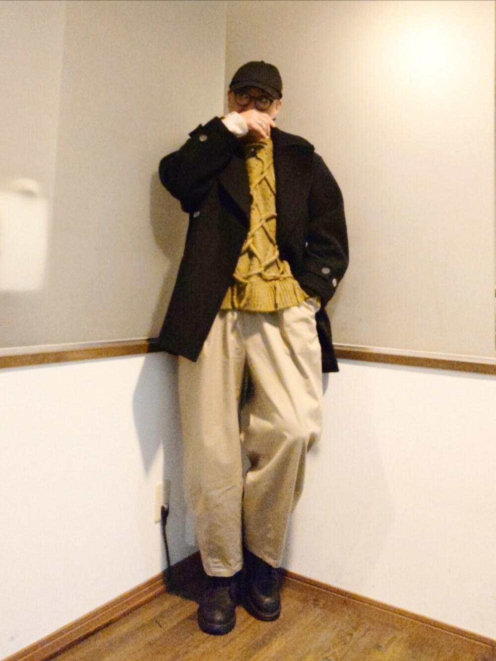 グリーン系のニット/セーター、ブラック系のピーコート、ベージュ系のチノパンツを着用したメンズの冬コーディネートの3枚目の写真