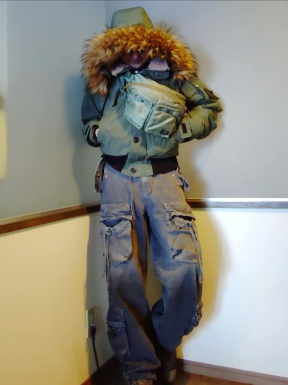 グリーン系のミリタリージャケット、グリーン系のボディバッグ/ウエストポーチ、ブラック系のカーゴパンツを着用したメンズの冬コーディネートの2枚目の写真