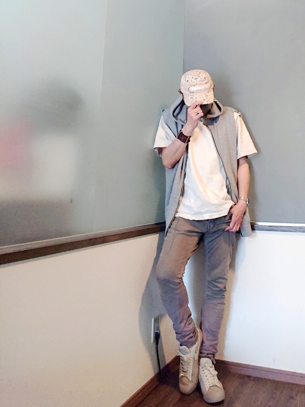 グレー系のベスト、ホワイト系のTシャツ/カットソー、ブラウン系のデニムパンツを着用したメンズの夏コーディネートの3枚目の写真