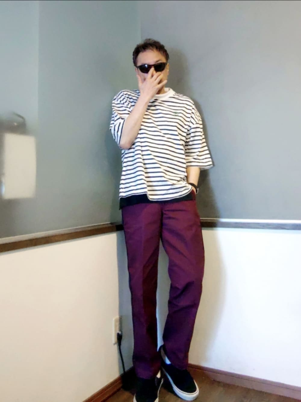 ホワイト系のTシャツ/カットソー、レッド系のチノパンツ、ブラック系のスニーカーを着用したメンズの夏コーディネートの2枚目の写真