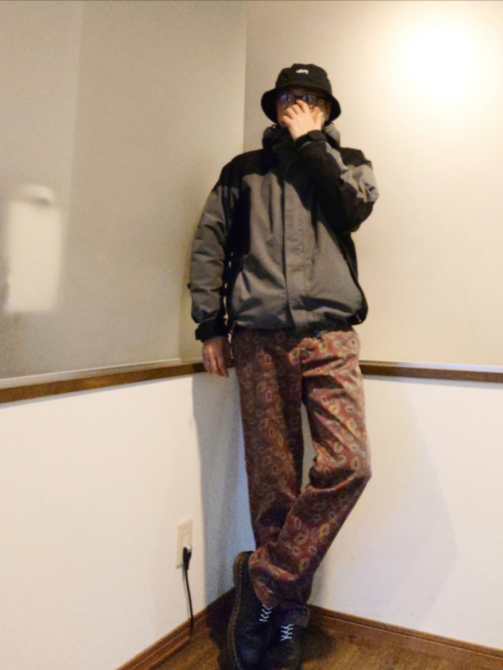 グレー系のマウンテンパーカー、ブルー系のニット/セーター、レッド系のチノパンツを着用したメンズの秋コーディネートの2枚目の写真