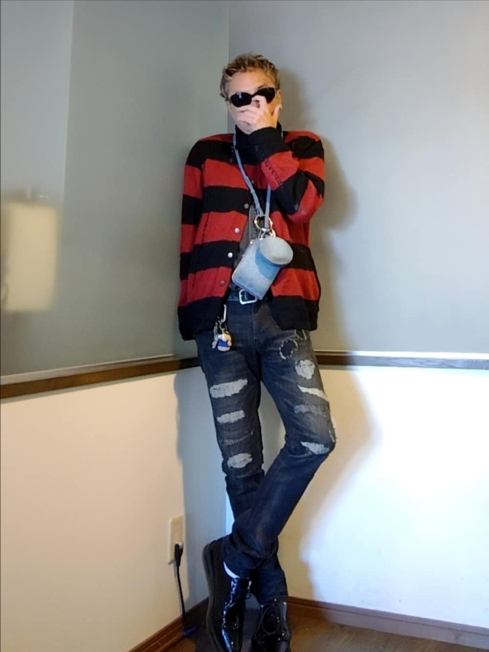 レッド系のカーディガン/ボレロ、ブラック系のシャツ/ブラウス、ブラック系のデニムパンツを着用したメンズの秋コーディネートの2枚目の写真