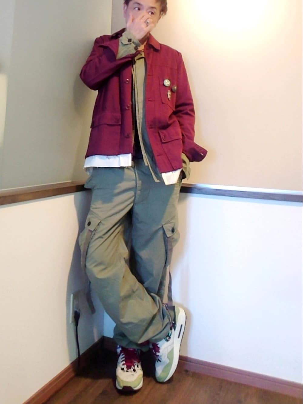 レッド系のカバーオール、グリーン系のカーゴパンツ、その他のスニーカーを着用したメンズの春コーディネートの2枚目の写真