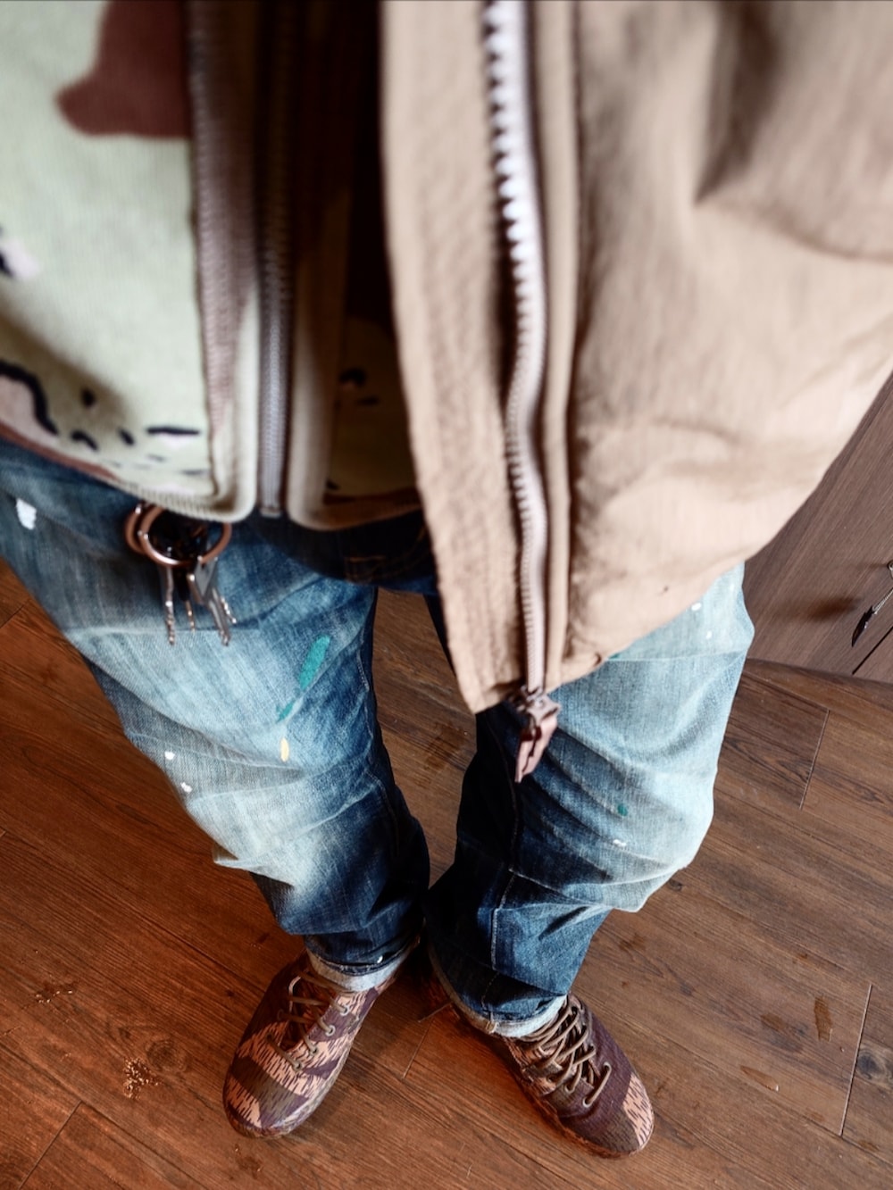 ブラウン系のベスト、ベージュ系のダウンジャケット/コート、ブルー系のデニムパンツを着用したメンズの冬コーディネートの4枚目の写真