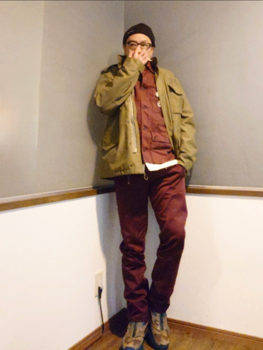 レッド系のカバーオール、グリーン系のミリタリージャケット、レッド系のチノパンツを着用したメンズの冬コーディネートの2枚目の写真