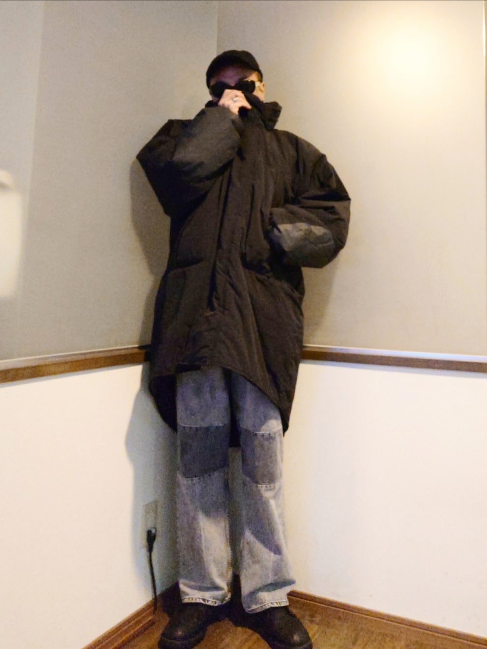 グレー系のデニムパンツ、グリーン系のニット/セーター、ブラック系のダウンジャケット/コートを着用したメンズの冬コーディネートの2枚目の写真