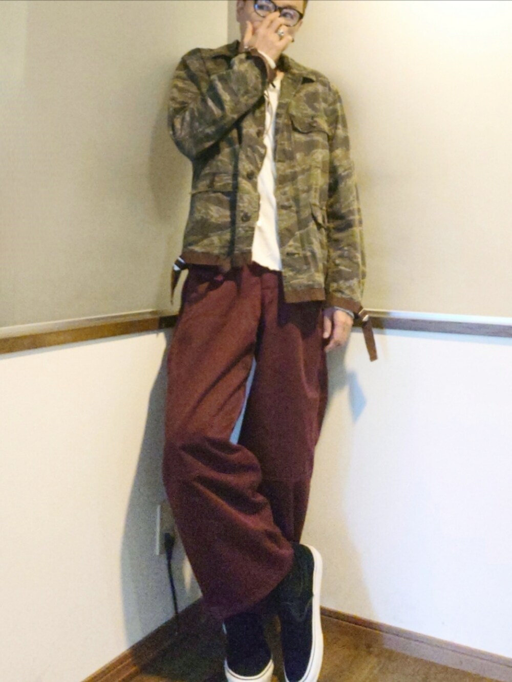 グリーン系のミリタリージャケット、レッド系のパンツ、ブラック系のスニーカーを着用したメンズの秋コーディネートの2枚目の写真