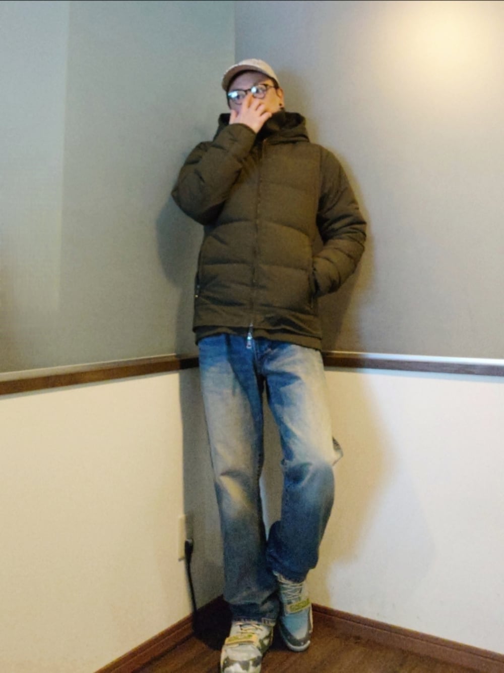 グリーン系のダウンジャケット/コート、ベージュ系のニット/セーター、ブルー系のデニムパンツを着用したメンズの冬コーディネートの2枚目の写真