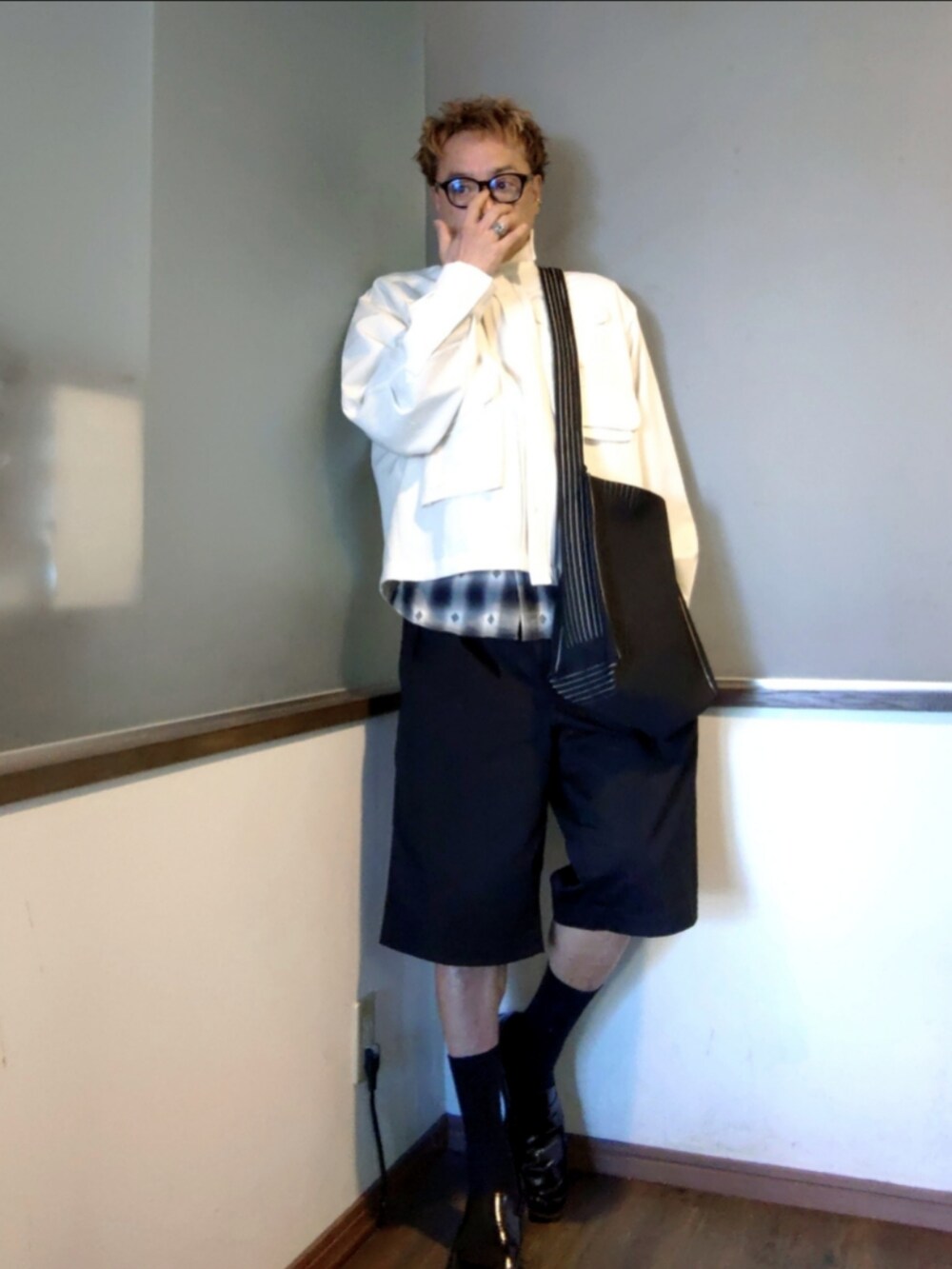 ホワイト系のミリタリージャケット、ブラック系のチノパンツ、ブラック系のショルダーバッグを着用したメンズの秋コーディネートの3枚目の写真