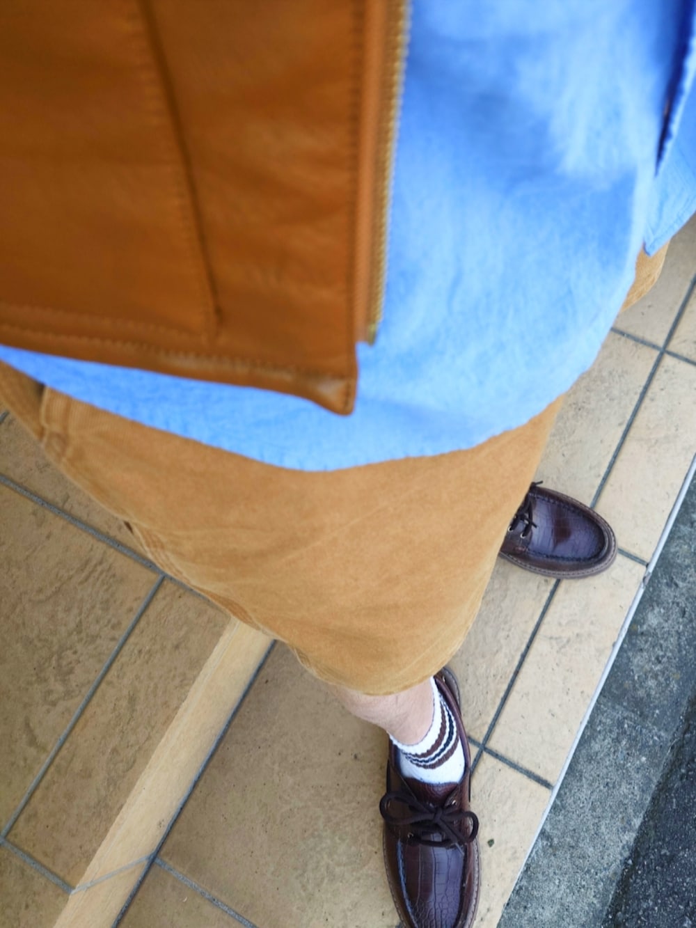 ブラウン系のダウンベスト、ブラウン系のパンツ、ブラウン系のモカシン/デッキシューズを着用したメンズの春コーディネートの4枚目の写真