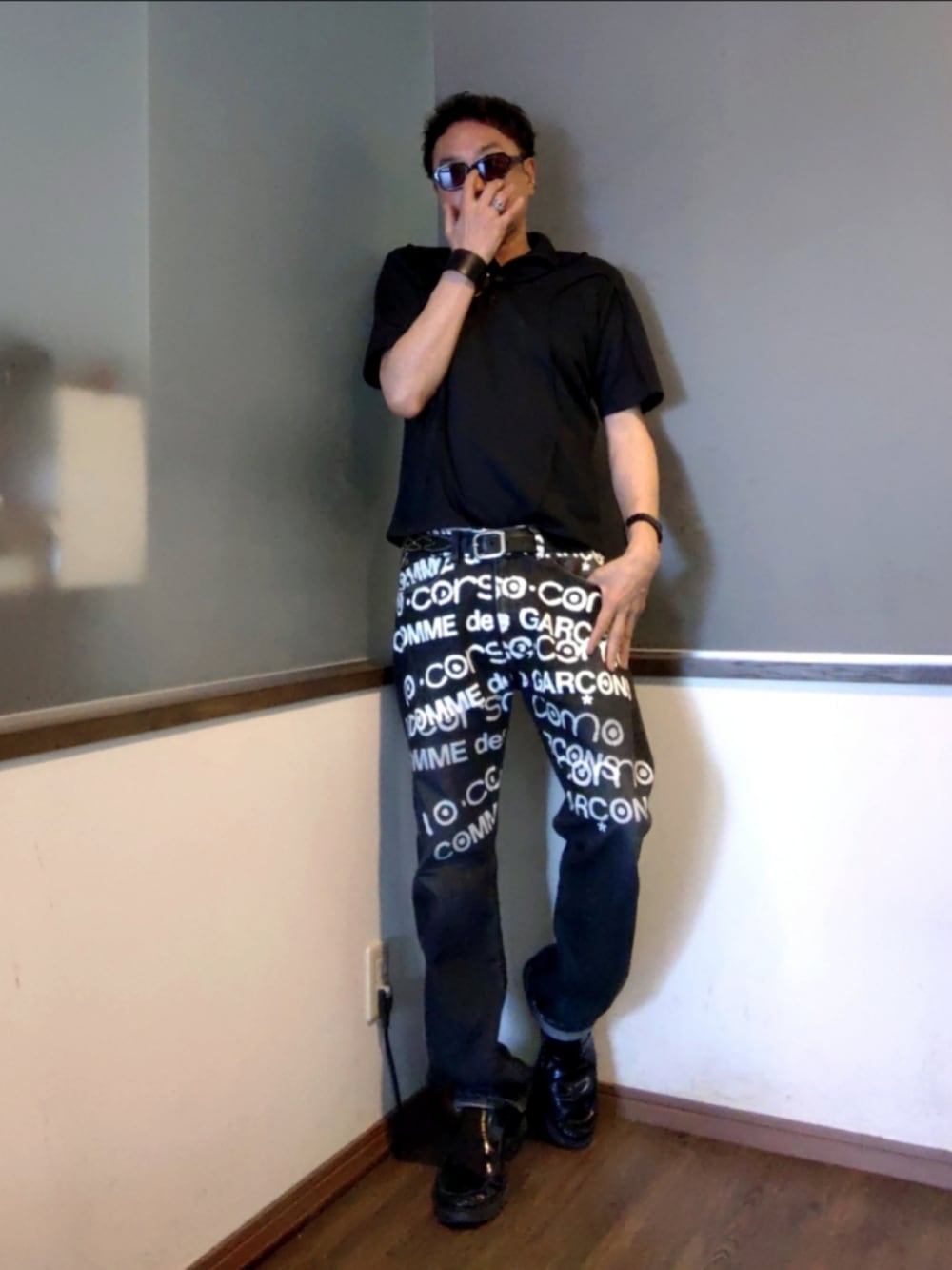 ブラック系のデニムパンツ、ブラック系のローファー、ブラック系のポロシャツを着用したメンズの夏コーディネートの2枚目の写真