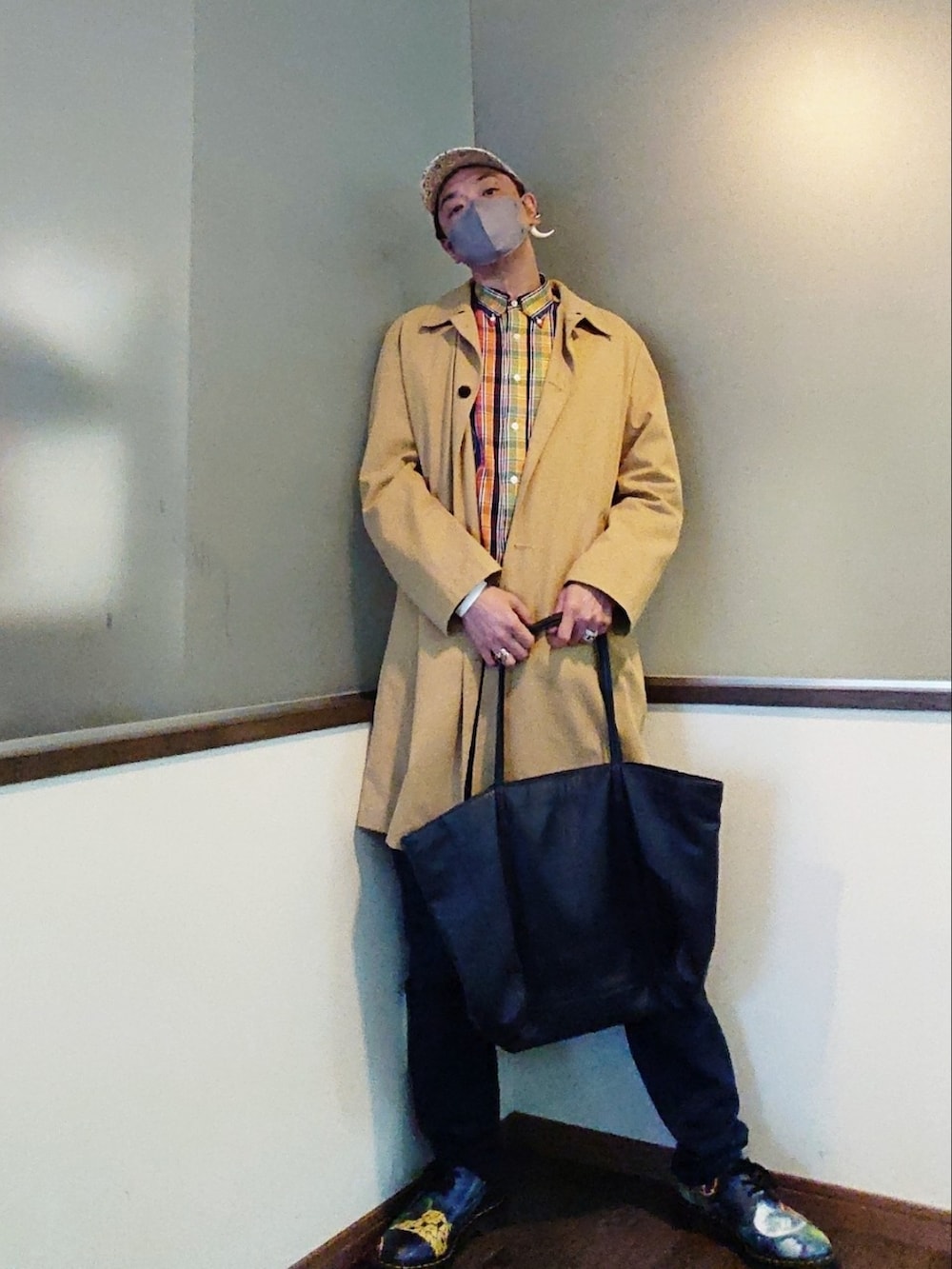 ベージュ系のステンカラーコート、イエロー系のシャツ/ブラウス、ブルー系のパンツを着用したメンズの春コーディネートの2枚目の写真