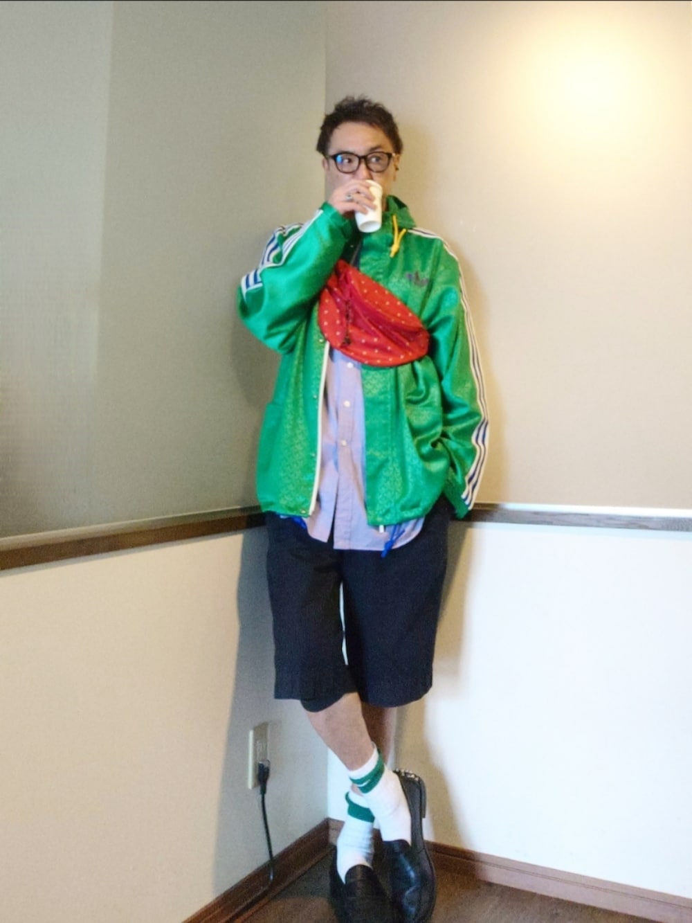 レッド系のショルダーバッグ、グリーン系のナイロンジャケット、パープル系のシャツ/ブラウスを着用したメンズの春コーディネートの2枚目の写真