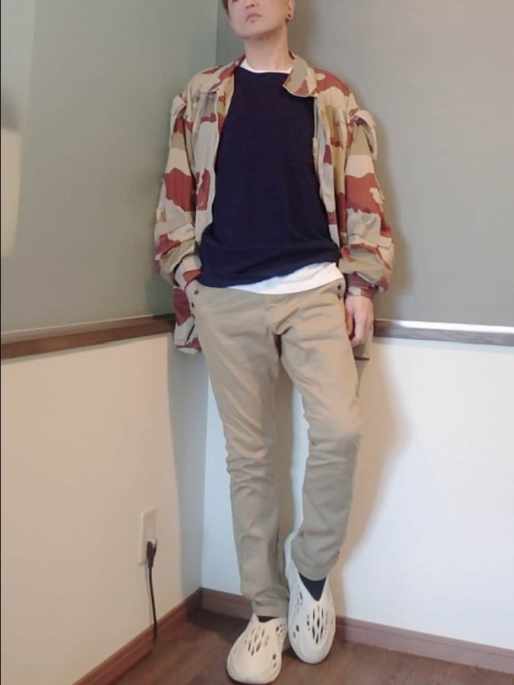 ベージュ系のミリタリージャケット、ブルー系のニット/セーター、ホワイト系のスニーカーを着用したメンズの春コーディネートの2枚目の写真