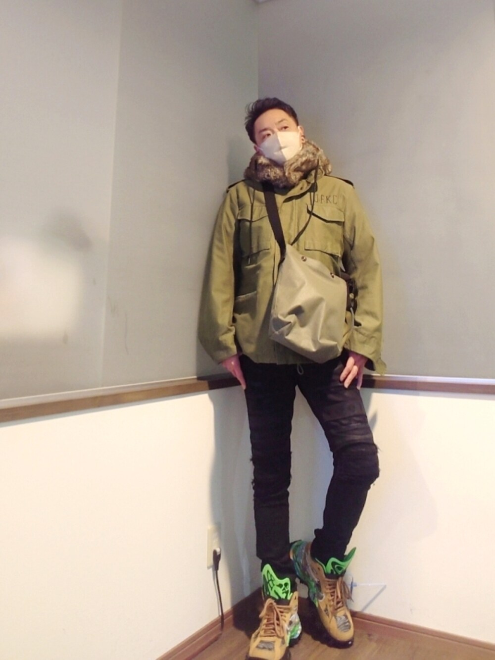 グリーン系のミリタリージャケット、ブラック系のデニムパンツ、ブラウン系のスニーカーを着用したメンズの冬コーディネートの2枚目の写真