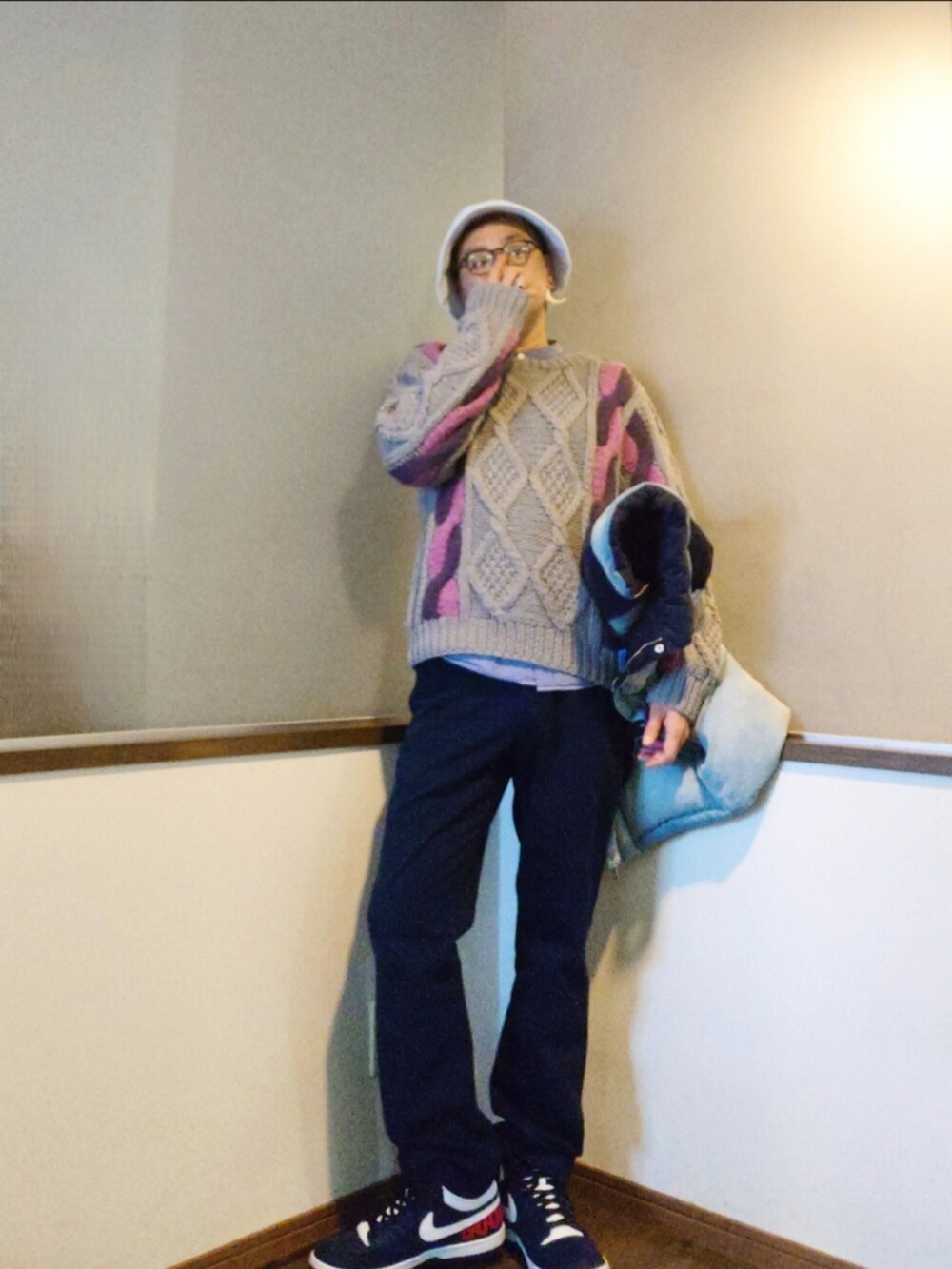 ブルー系のダウンベスト、グレー系のニット/セーター、ブルー系のスラックスを着用したメンズの秋コーディネートの2枚目の写真