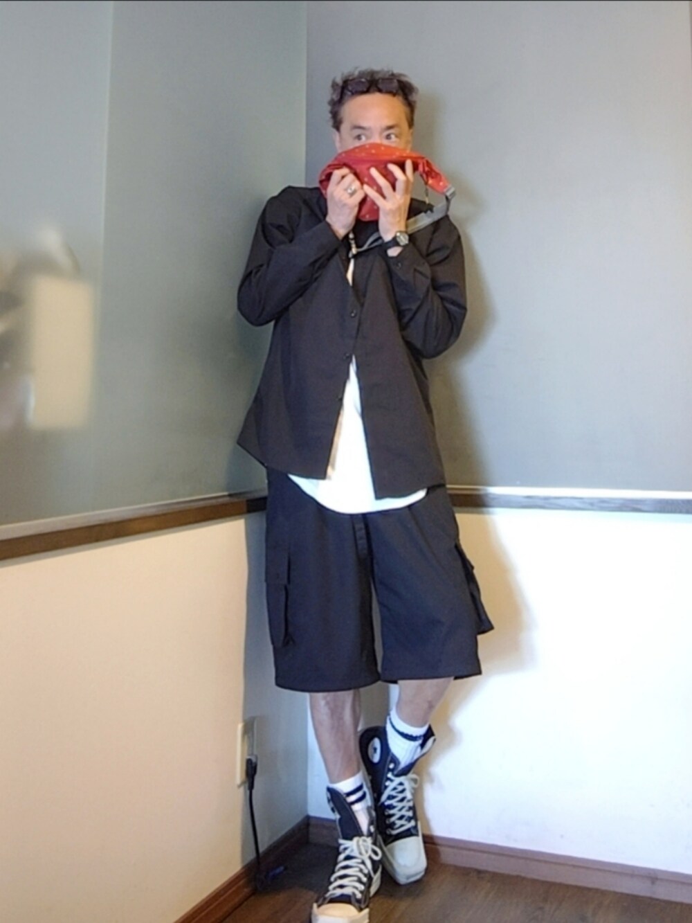 ブラック系のスニーカー、レッド系のショルダーバッグ、ブラック系のカーゴパンツを着用したメンズの夏コーディネートの3枚目の写真