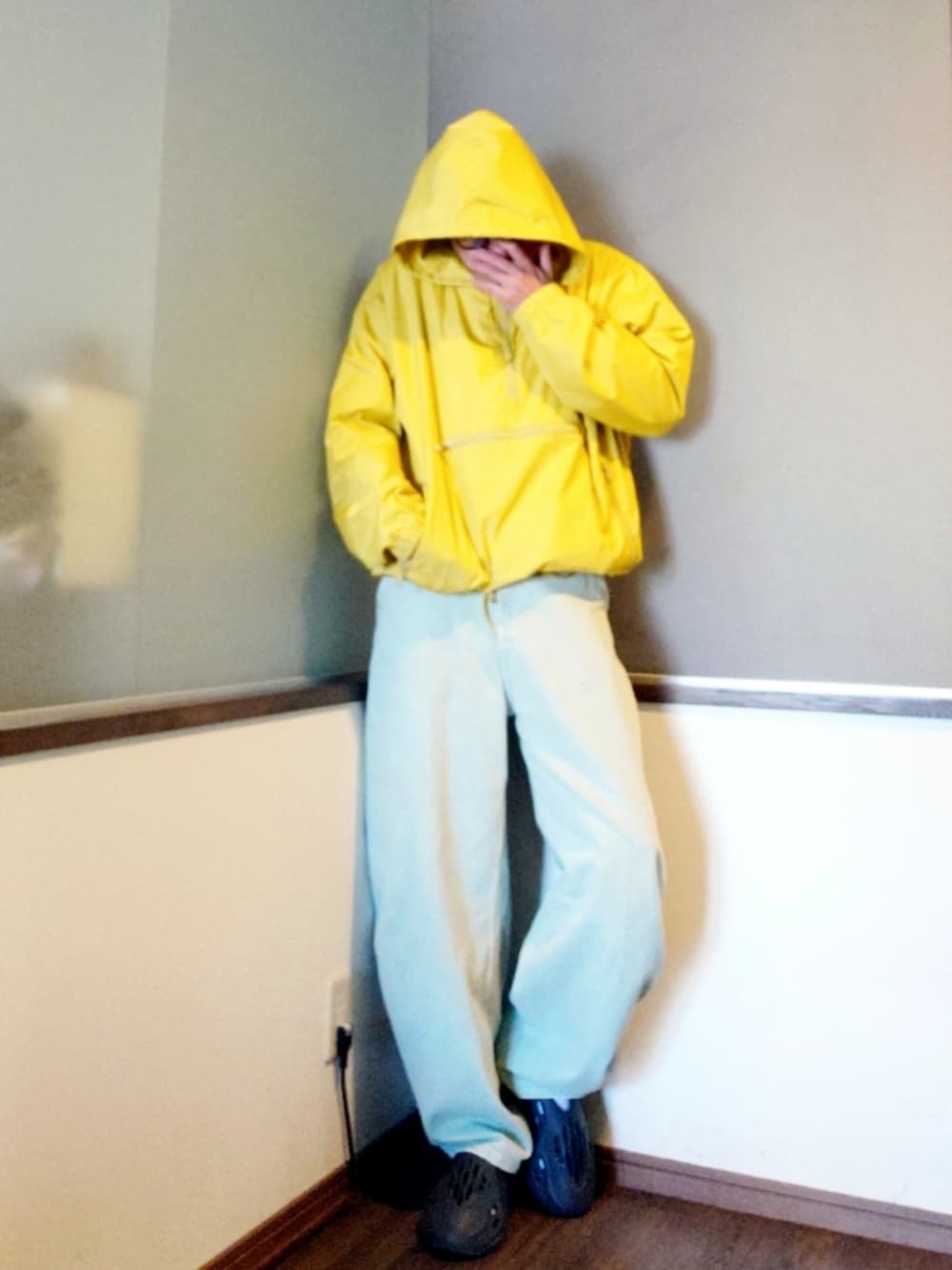 イエロー系のナイロンジャケット、ブルー系のデニムパンツ、グレー系のシューズを着用したメンズの春コーディネートの2枚目の写真