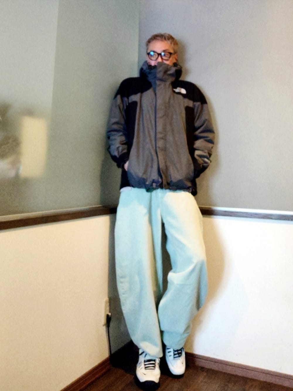 グレー系のマウンテンパーカー、グリーン系のニット/セーター、ブルー系のデニムパンツを着用したメンズの春コーディネートの3枚目の写真