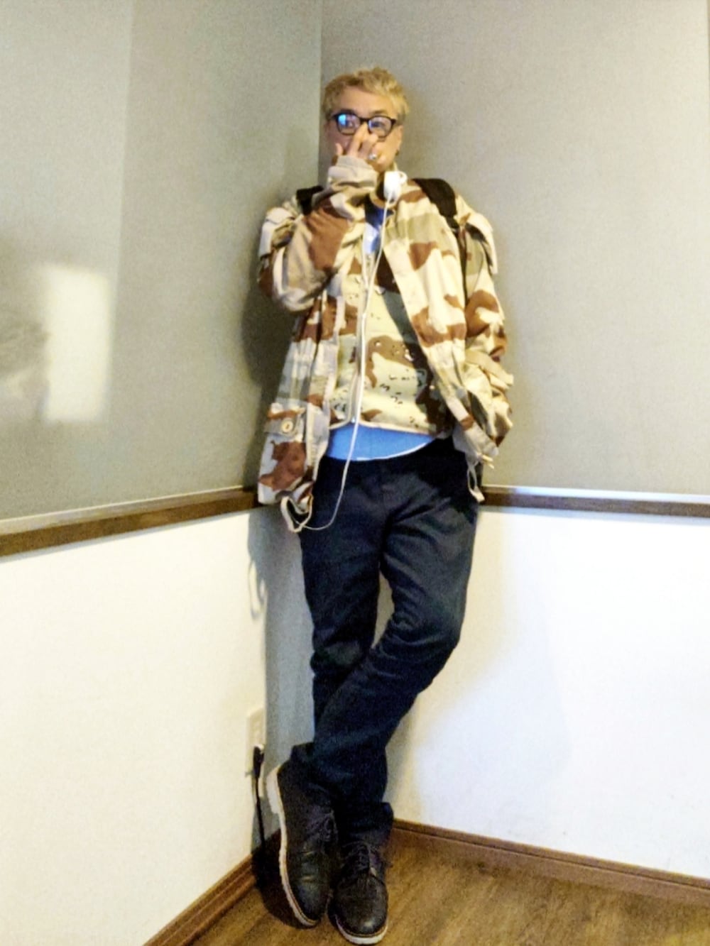 ブラウン系のベスト、ベージュ系のミリタリージャケット、ブラック系のバックパック/リュックを着用したメンズの春コーディネートの2枚目の写真