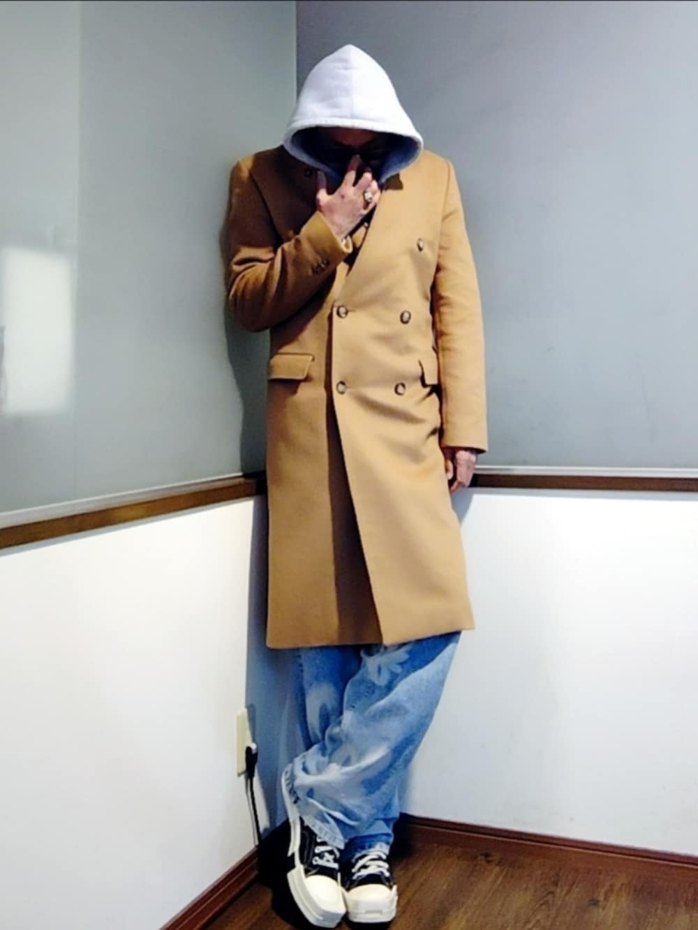 グレー系のパーカー、ベージュ系のチェスターコート、ホワイト系のTシャツ/カットソーを着用したメンズの冬コーディネートの2枚目の写真