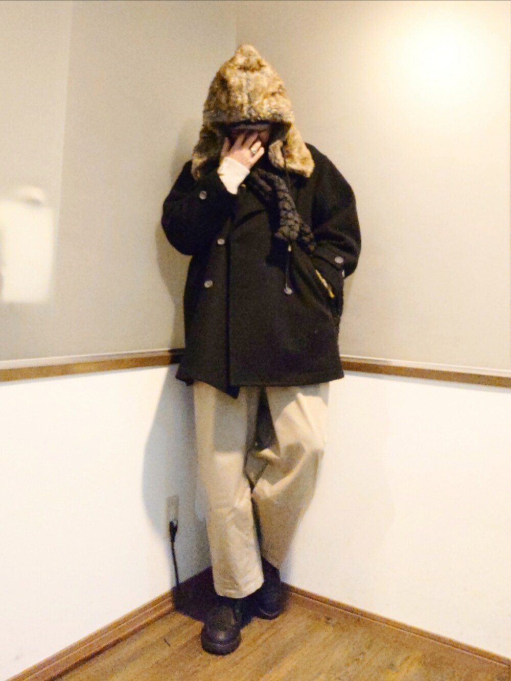 グリーン系のニット/セーター、ブラック系のピーコート、ベージュ系のチノパンツを着用したメンズの冬コーディネートの2枚目の写真