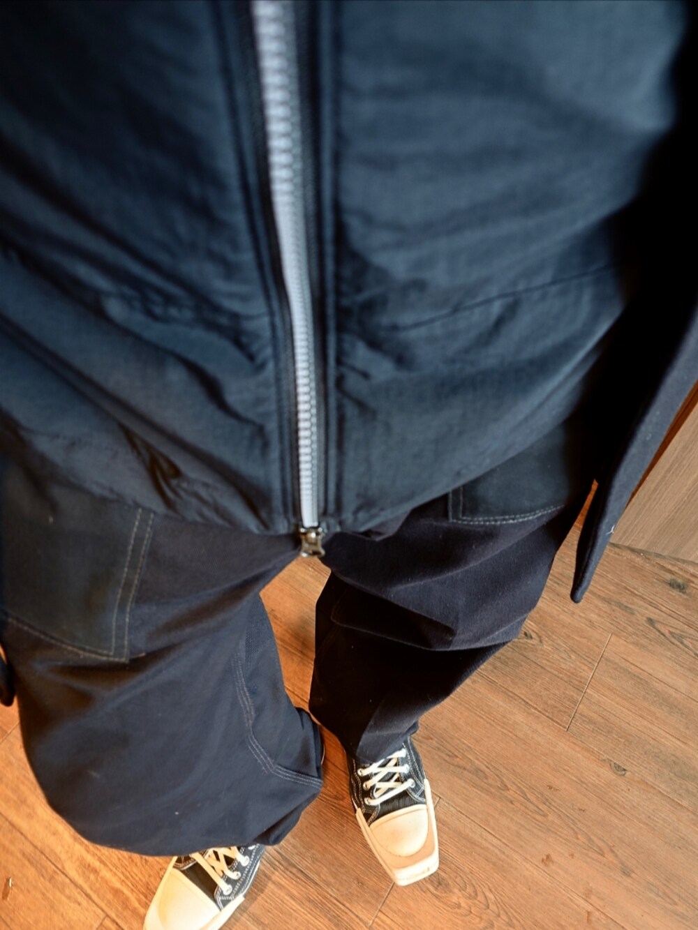 ブラック系のナイロンジャケット、ブラック系のチェスターコート、ブラック系のチノパンツを着用したメンズの冬コーディネートの2枚目の写真