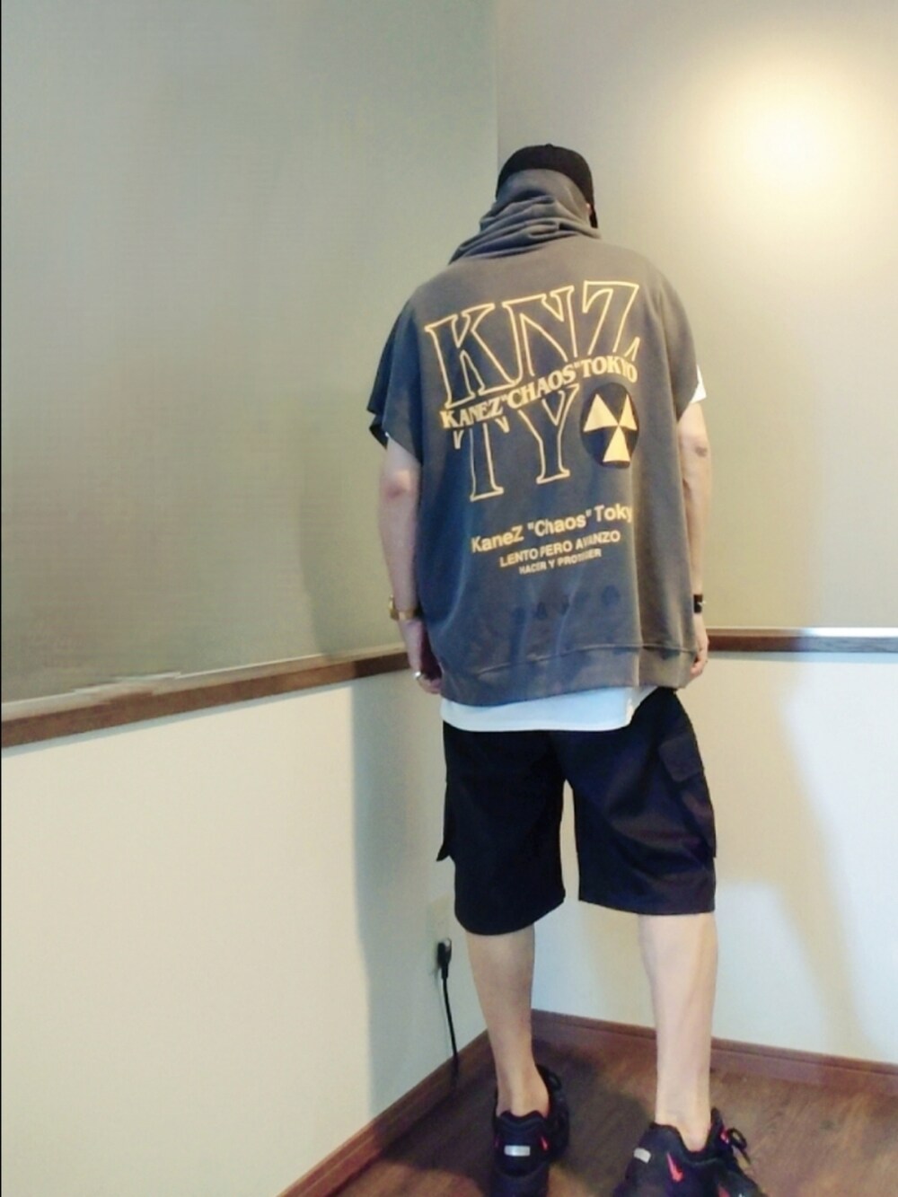 グレー系のパーカー、ブラック系のカーゴパンツ、ブラック系のスニーカーを着用したメンズの夏コーディネートの4枚目の写真