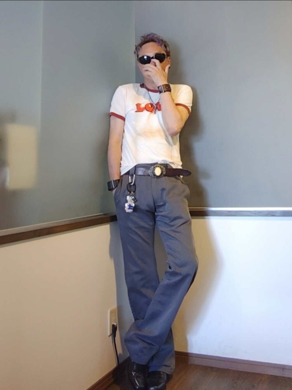 ベージュ系のTシャツ/カットソー、グレー系のチノパンツ、ブラック系のブーツを着用したメンズの夏コーディネートの2枚目の写真