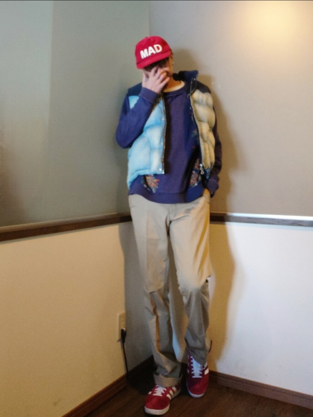 ブルー系のニット/セーター、ブルー系のダウンベスト、レッド系のスニーカーを着用したメンズの冬コーディネートの2枚目の写真