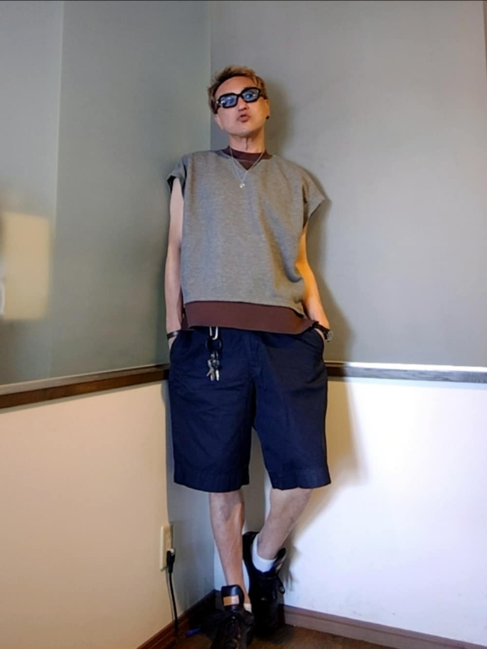 グレー系のベスト、ブルー系のチノパンツ、ブラウン系のスニーカーを着用したメンズの夏コーディネートの2枚目の写真