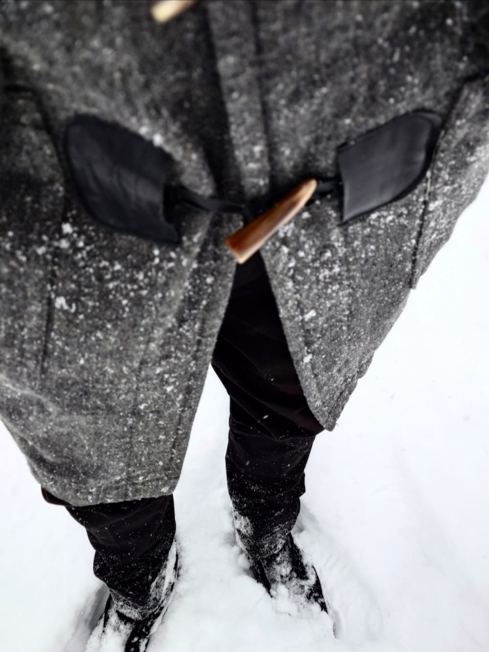 グレー系のダッフルコート、ブラウン系のニット/セーター、ブラック系のパンツを着用したメンズの冬コーディネートの4枚目の写真