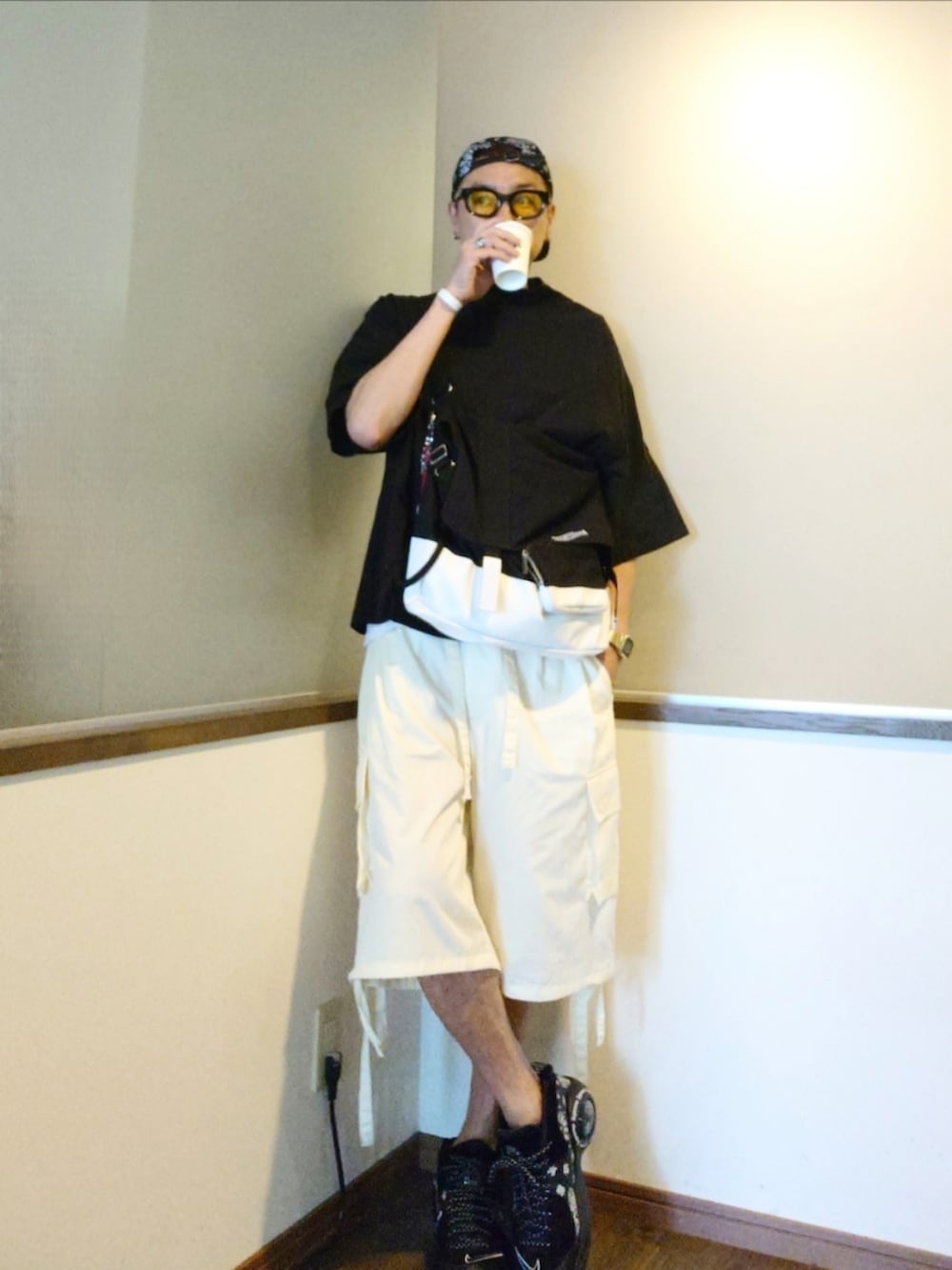 ブラック系のTシャツ/カットソー、イエロー系のカーゴパンツ、ホワイト系のショルダーバッグを着用したメンズの夏コーディネートの2枚目の写真
