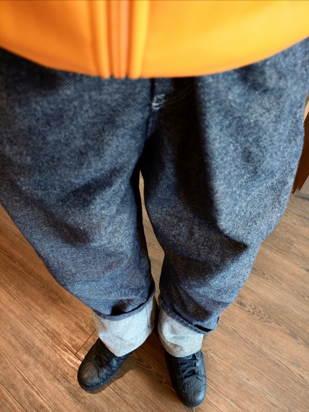 イエロー系のジャージ、ブルー系のデニムパンツ、ブラック系のスニーカーを着用したメンズの秋コーディネートの2枚目の写真