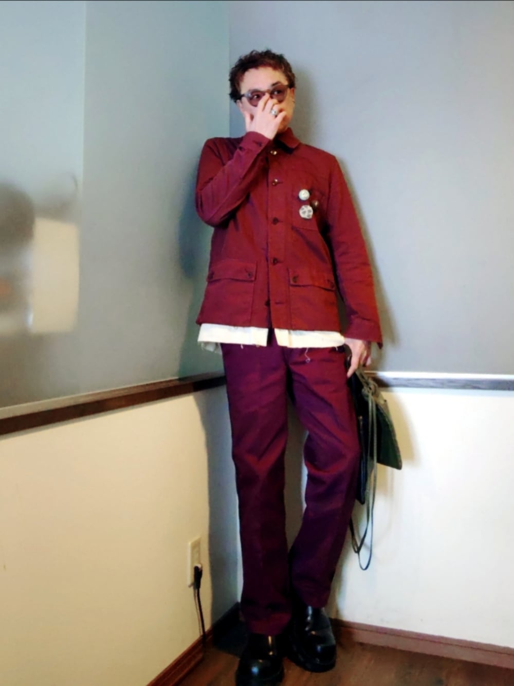 レッド系のチノパンツ、レッド系のカバーオール、ブラック系のカーディガン/ボレロを着用したメンズの春コーディネートの2枚目の写真