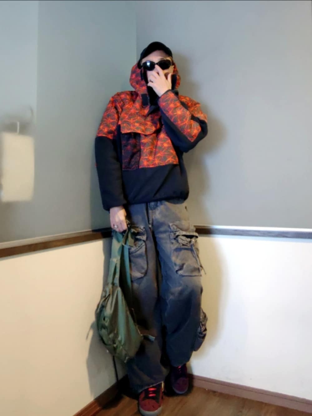 レッド系のブルゾン、ブラック系のカーゴパンツ、レッド系のスニーカーを着用したメンズの春コーディネートの2枚目の写真