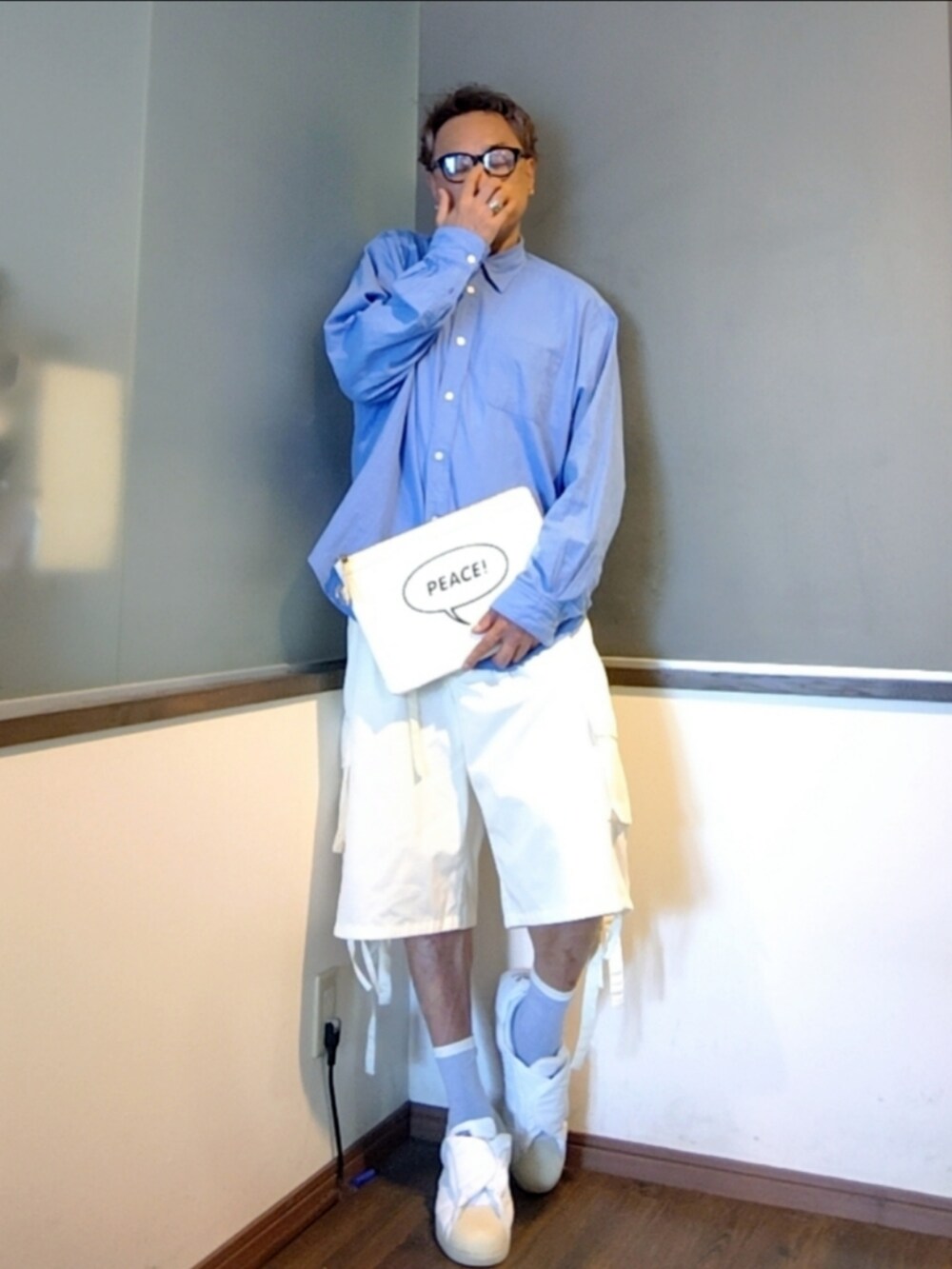 ホワイト系のクラッチバッグ、ブルー系のシャツ/ブラウス、ホワイト系のスニーカーを着用したメンズの夏コーディネートの2枚目の写真