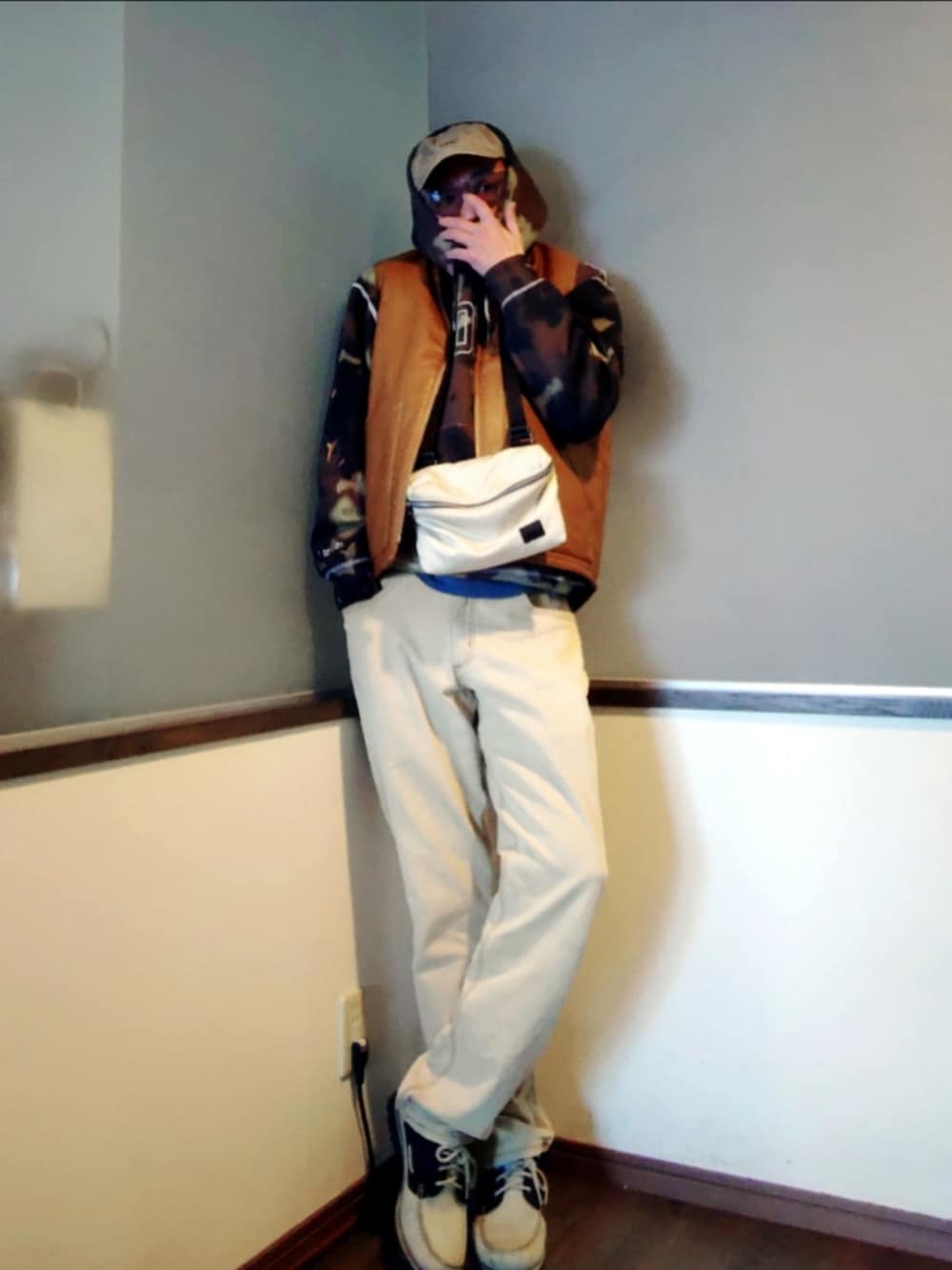 ブラウン系のダウンベスト、ブラック系のパーカー、ブラウン系のパンツを着用したメンズの春コーディネートの2枚目の写真