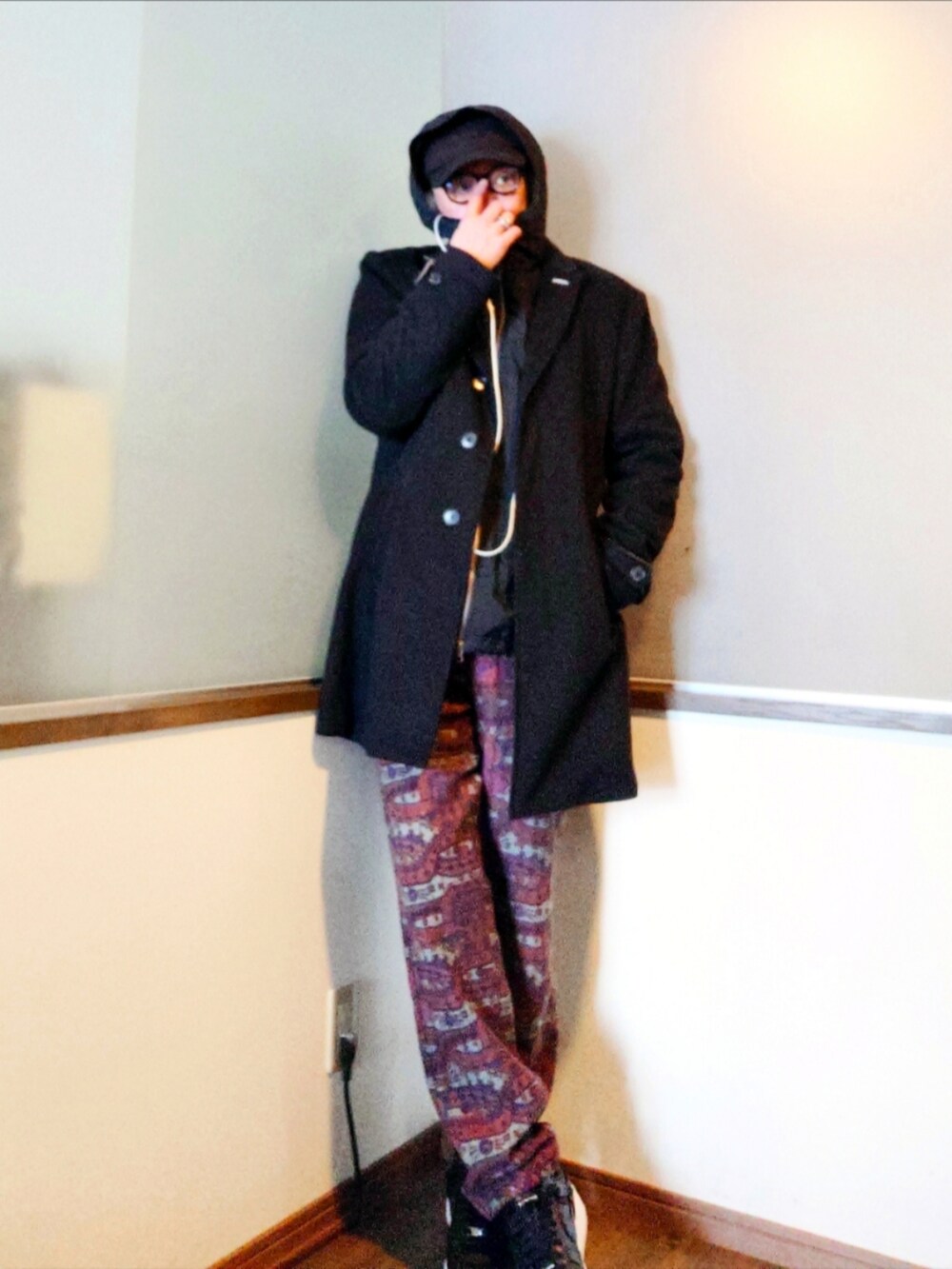 ブラック系のチェスターコート、ブラック系のナイロンジャケット、レッド系のパンツを着用したメンズの冬コーディネートの2枚目の写真