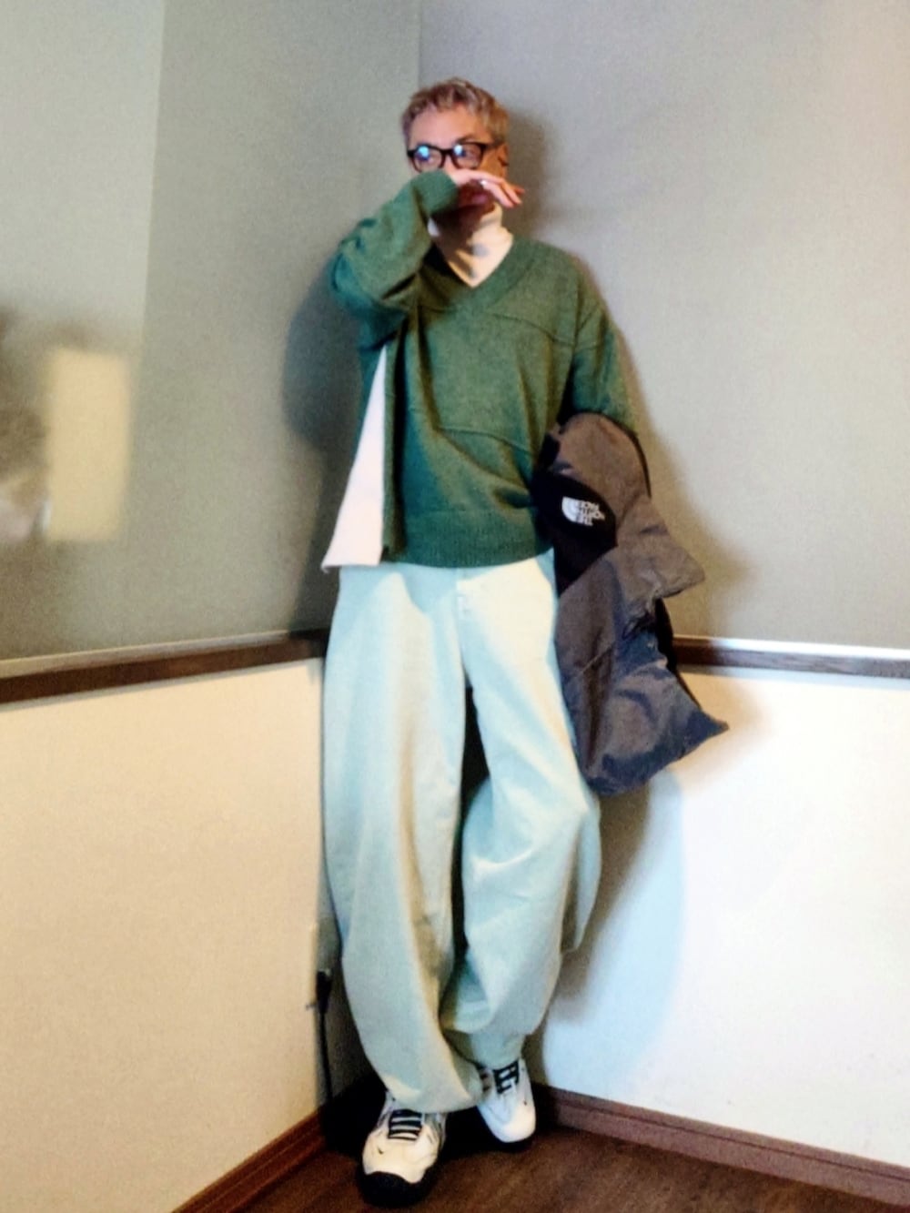 グレー系のマウンテンパーカー、グリーン系のニット/セーター、ブルー系のデニムパンツを着用したメンズの春コーディネートの2枚目の写真