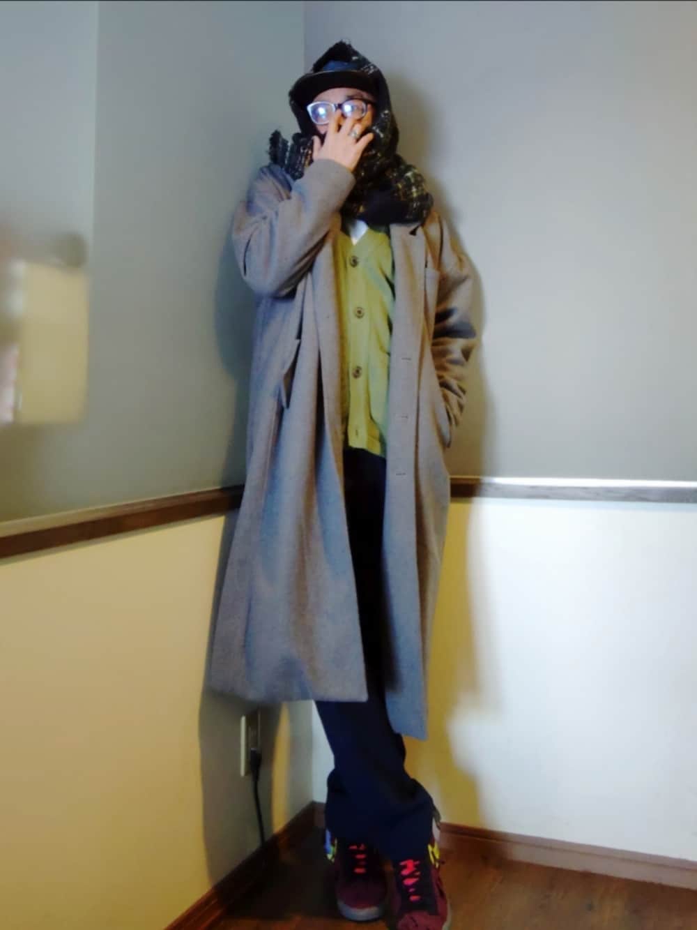 グレー系のチェスターコート、ブルー系のスラックス、レッド系のスニーカーを着用したメンズの冬コーディネートの2枚目の写真