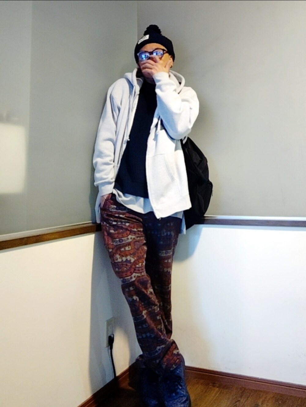 グレー系のパーカー、レッド系のパンツ、ブルー系のスニーカーを着用したメンズの秋コーディネートの3枚目の写真