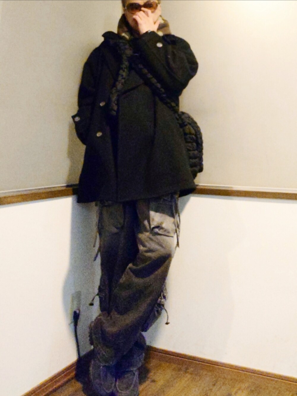 ブラック系のパーカー、ブラック系のショルダーバッグ、ブラック系のピーコートを着用したメンズの冬コーディネートの3枚目の写真