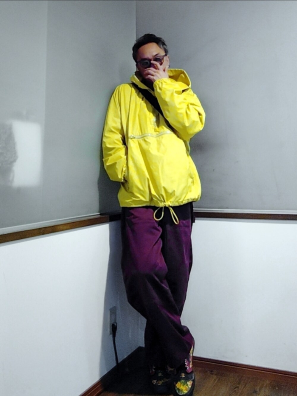 グレー系のスウェット、レッド系のパンツ、イエロー系のナイロンジャケットを着用したメンズの秋コーディネートの2枚目の写真