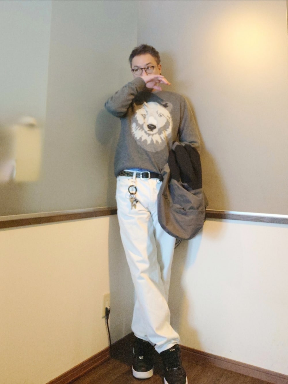 グレー系のマウンテンパーカー、グレー系のニット/セーター、ホワイト系のデニムパンツを着用したメンズの冬コーディネートの3枚目の写真
