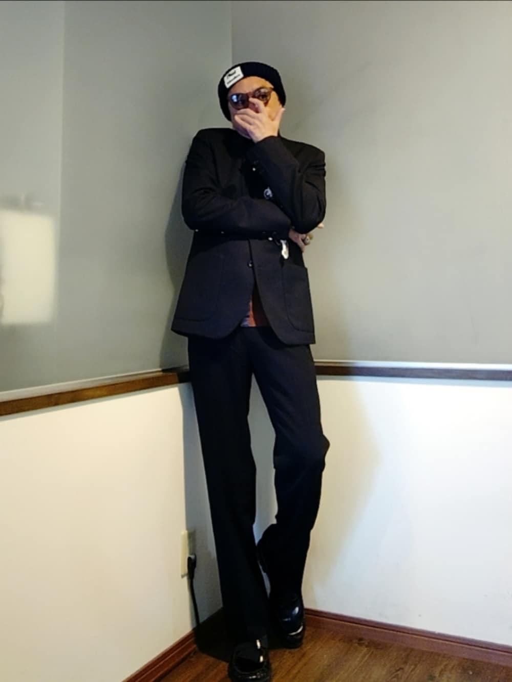 グレー系のテーラードジャケット、ブラウン系のカーディガン/ボレロ、ブラック系のスラックスを着用したメンズの秋コーディネートの3枚目の写真