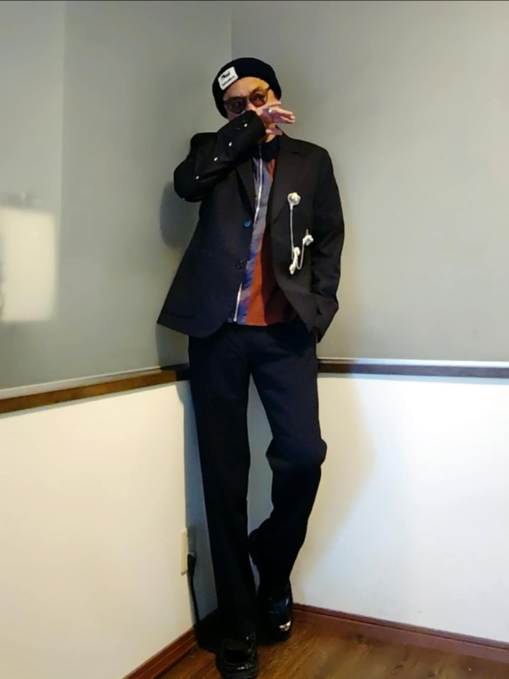 グレー系のテーラードジャケット、ブラウン系のカーディガン/ボレロ、ブラック系のスラックスを着用したメンズの秋コーディネートの2枚目の写真