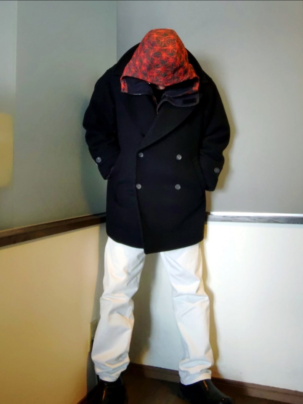 レッド系のブルゾン、ブラック系のピーコート、ホワイト系のデニムパンツを着用したメンズの冬コーディネートの3枚目の写真